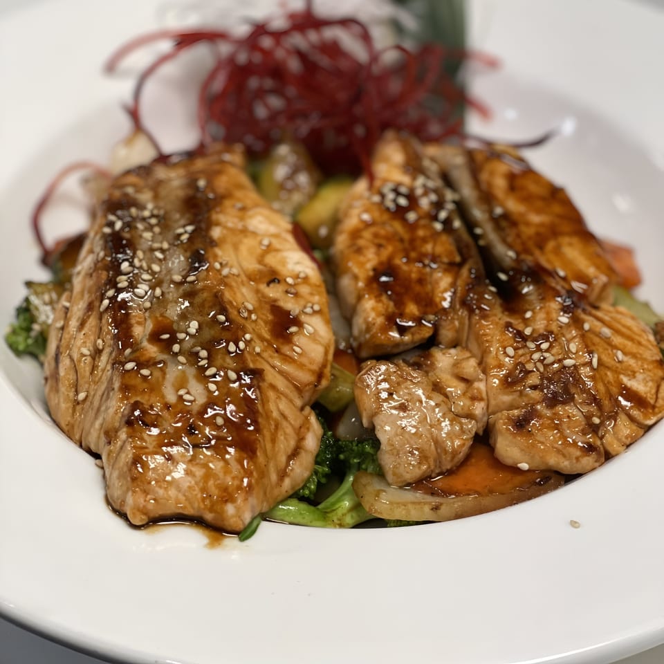 Teriyaki salmon with sesame seeds, broccoli, and other vegetables on a white plate at Saisaki Fort Wayne.