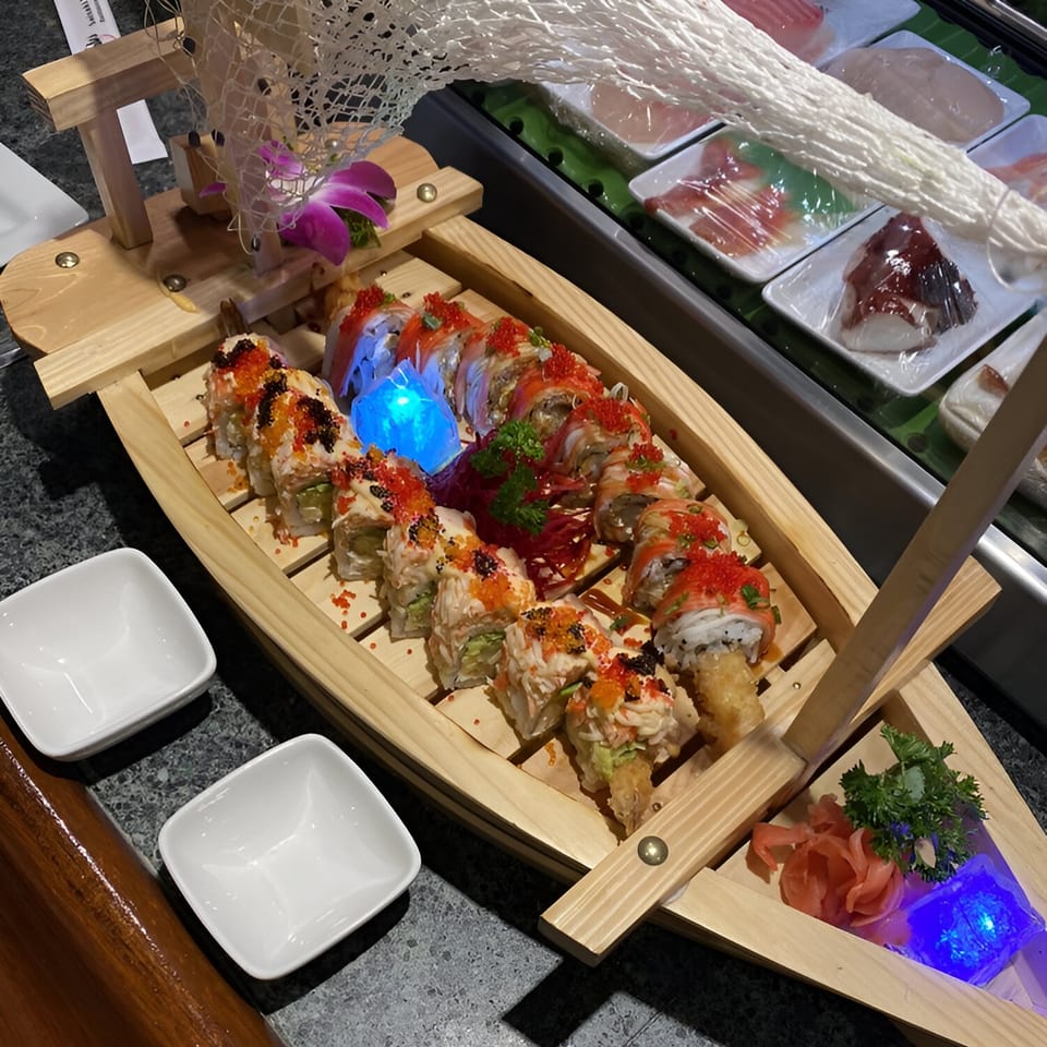A sushi boat from Saisaki Fort Wayne, filled with various sushi rolls, ginger, and parsley.